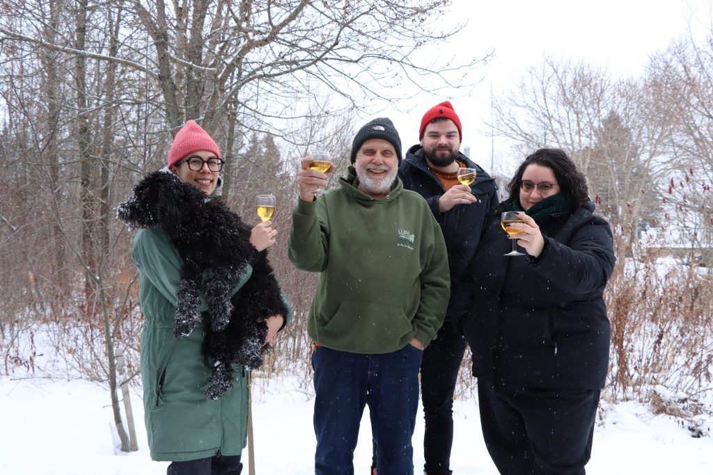 L'équipe d'Est-Nord-Est levant un verre de moût de pomme. Il neige tranquillement. Ils sont contents